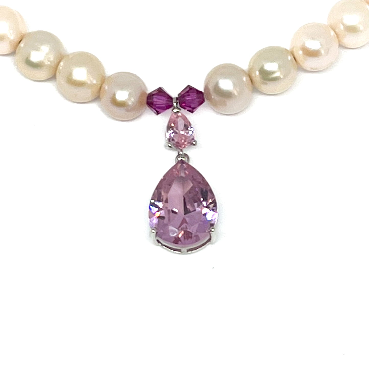 Close up of an Amethyst Tear Drop Pendant on a White Pearl Necklace.