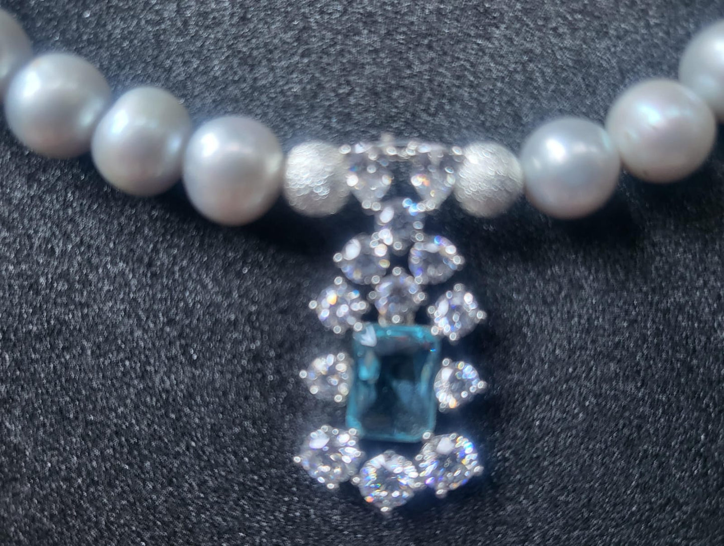 Close up of 8-9mm AAA Quality Freshwater Pearl Necklace in Silver with Aquamarine Party Drop with black background.