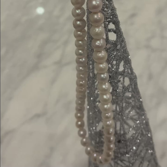 Video of 10mm AAA Quality Freshwater Cultured Pearl Necklace in White hung from an ornament and a gold floral pattern background.